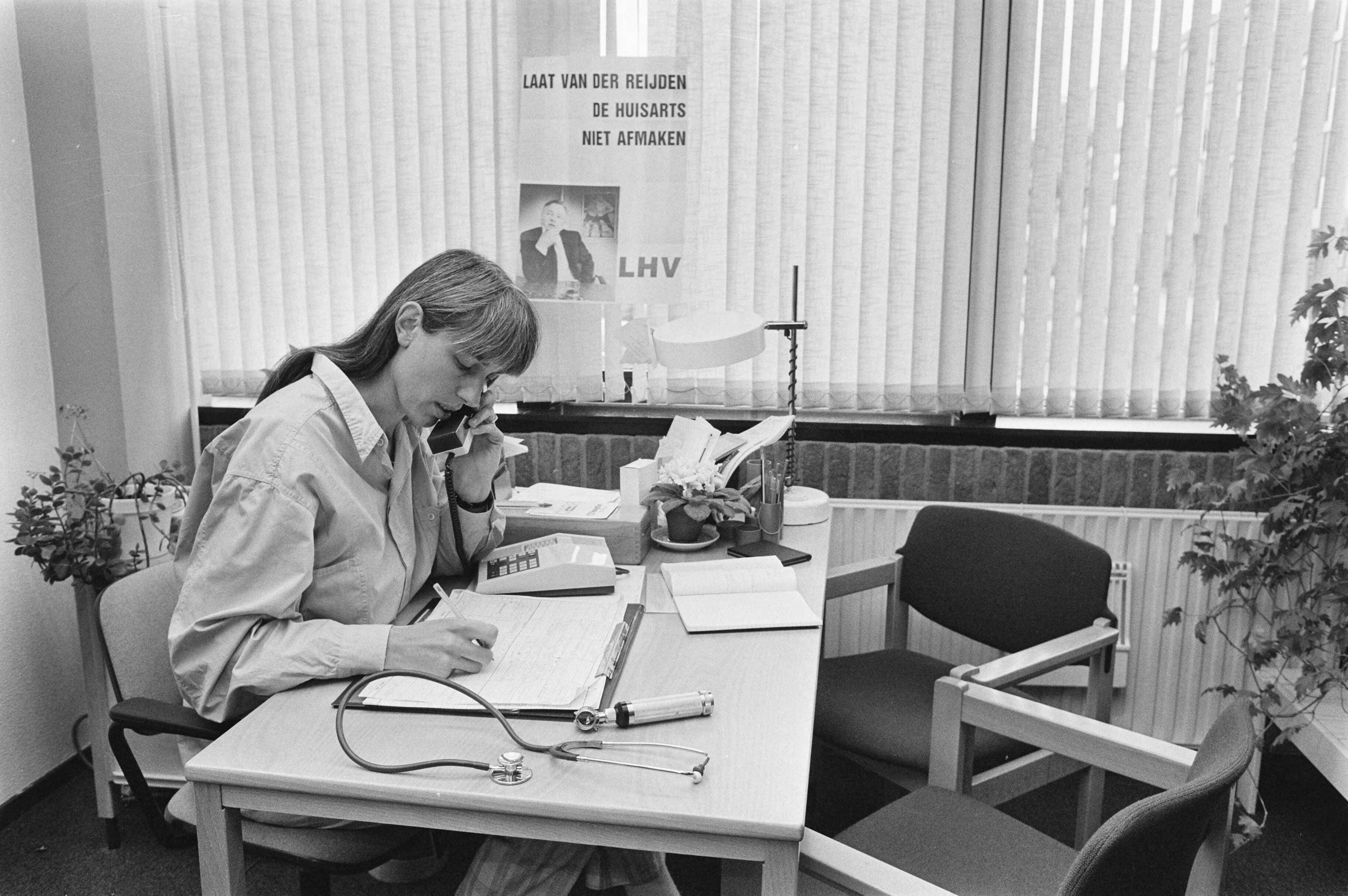Amsterdamse huisarts Wanrooy aan de telefoon met papierwerk voor zich, 27 mei 1986.